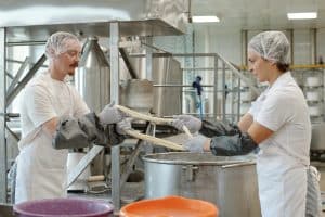 Dónde sacar el carnet de manipulador de alimentos: manipuladores con redecilla y guantes en una cocina industrial